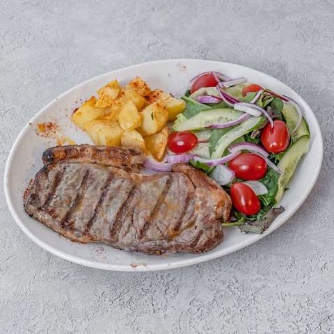 Minute steak with salad and roast potatoes on a white oval plate