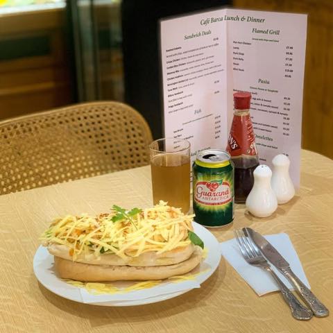 A laid table inside, with a cane chair and the printed lunch card propped against the wall