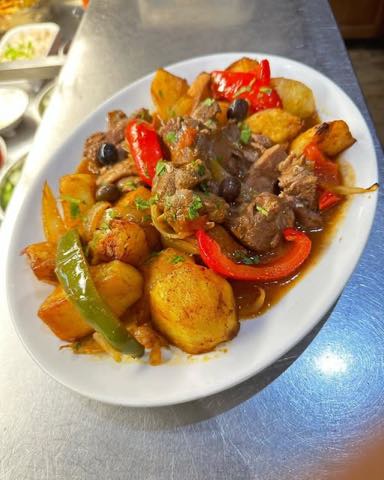 A meat and potato stew with red and green peppers and olives